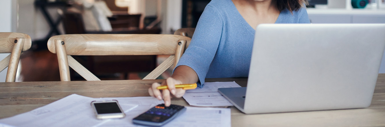 Individual on computer and using a calculator