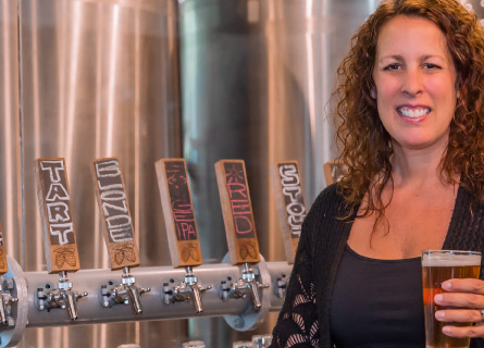 a person holding a beverage at their brewery.